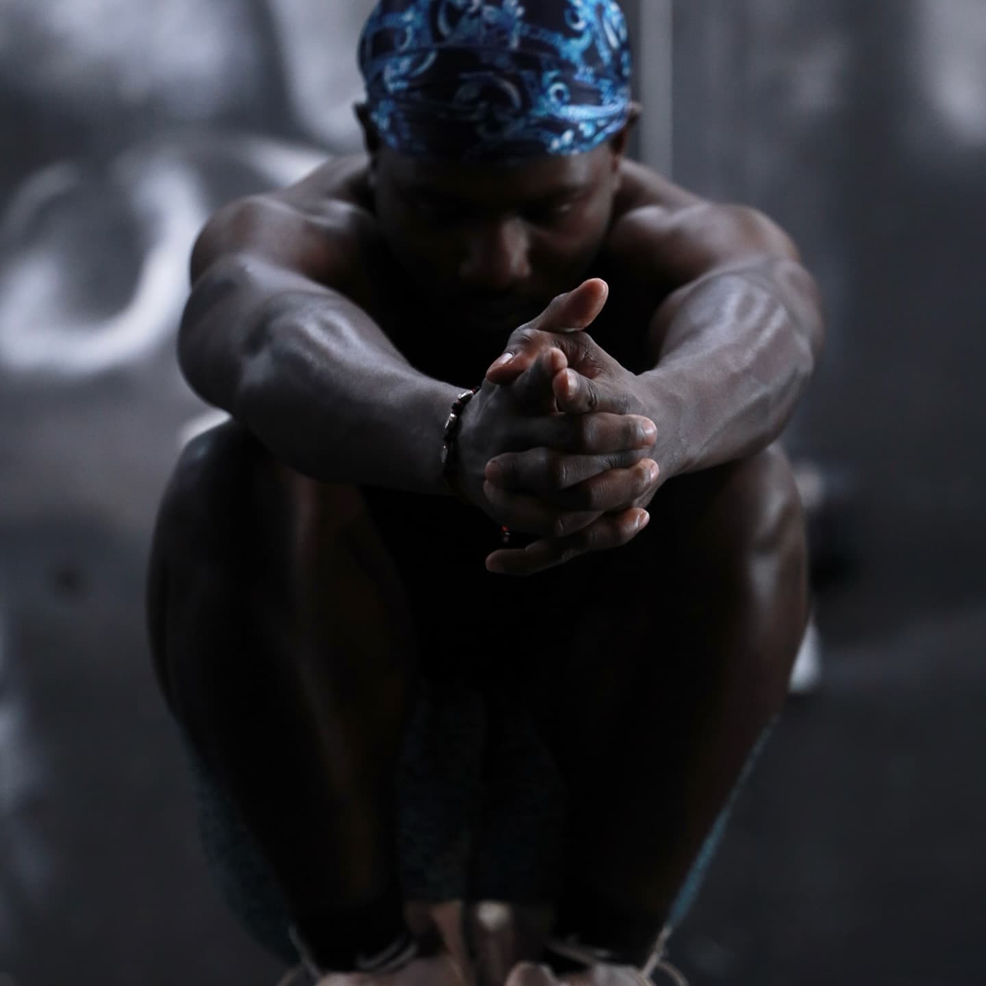 Moody portrait of Kenneth Sene in a blue durag, hands clasped